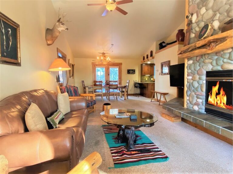 Whitefish lake vacation rental family room with fireplace and dinning room. Deer on wall