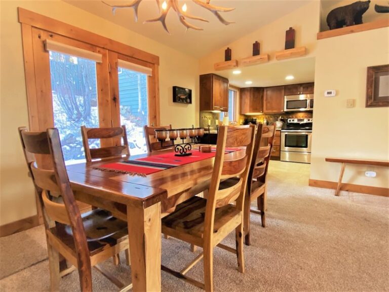 Whitefish lake vacation rental dinning room with antler chandelier and kitchen stainless steel appliances. 